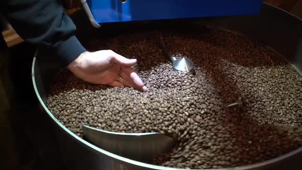 Coffee bean roaster mixing machine with Roastmaster sampling the batch by hand, Slow motion close up