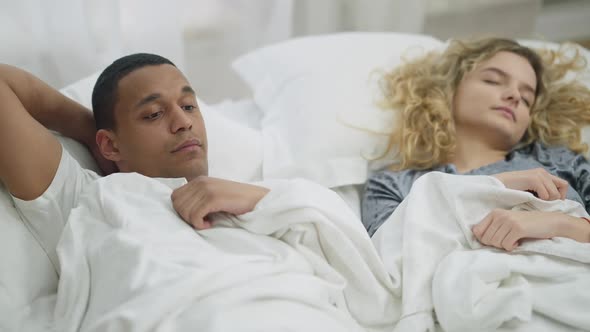 Young Happy Boyfriend Admiring Sleeping Girlfriend and Looking at Camera Smiling