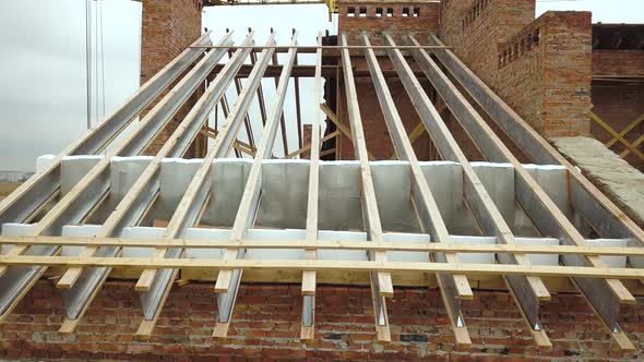 Aerial view of unfinished brick apartment building with wooden roof structure under construction.