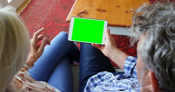 Senior couple using digital tablet on sofa at home 4k