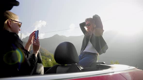 Girls Take Photos on a Smartphone Inside a Red Convertible