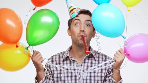 Funny Young Caucasian Male with Dark Hair and Light Bristle Wearing Birthday Cap Cheerfully Hiding