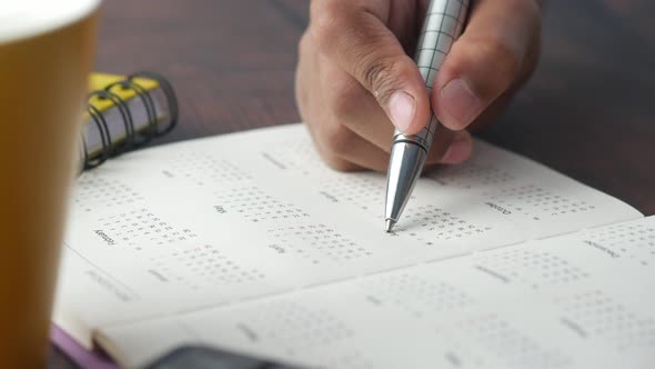 Hand with a Pen Marking on a Calendar