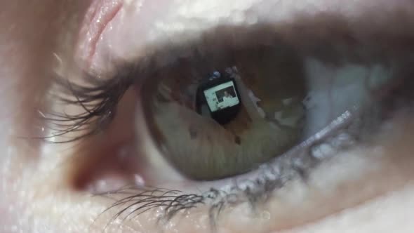 Macro close up, reflection of screen in females eye watching online video