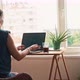 A Woman Working on a Laptop While Sitting at the Table Opposite a Window - VideoHive Item for Sale