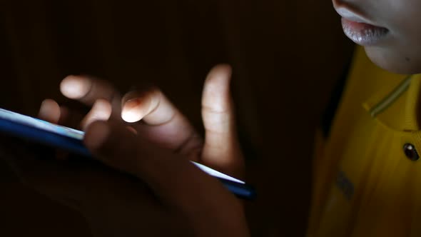 Teenage Boy Sitting on Sofa Using Smart Phone at Night