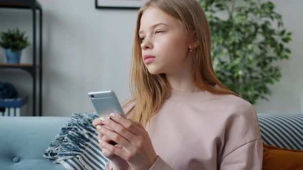 Slow Motion of Serious Teen Child Using Smartphone Messaging Indoors in Apartment