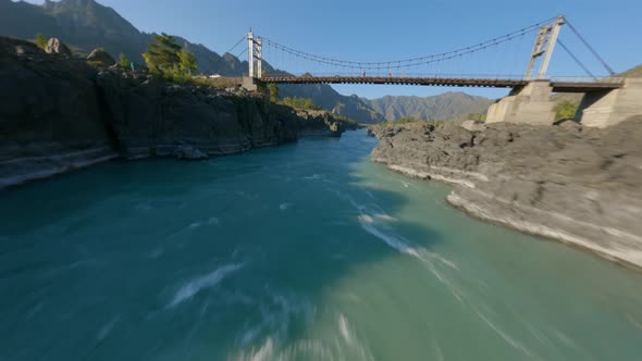 Aerial Rotation View Extreme Travel Couple on Top of Walking Bridge Over Mountain River Independence