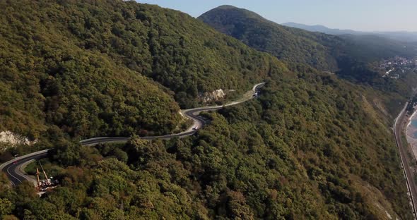 Aerial View of Car Driving Along The Winding Mountain Pass Road Through The Forest Trees. Autumn