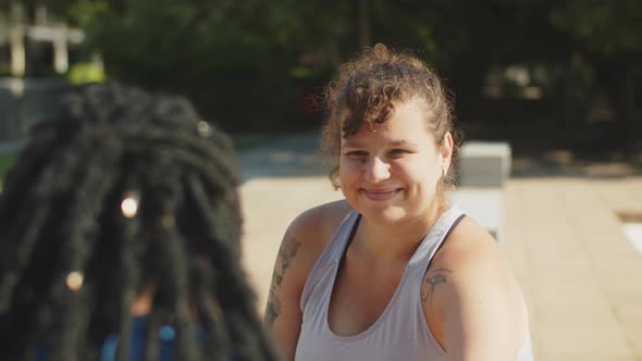 Slow Motion of Smiling Woman Stretching Legs with Friend in Park