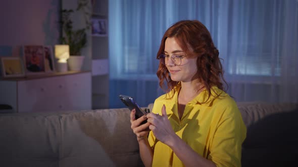 Woman with Glasses Uses Modern Technologies and Orders Fast Food From an Online Store Sitting on