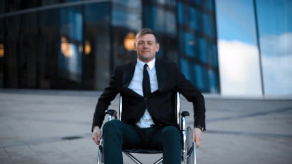 Impaired Happy Business Man Rolling in Wheelchair in the City