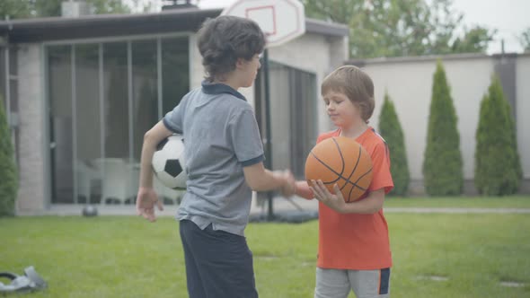 Charming Boys with Sport Balls Shaking Hands and Smiling at Camera. Portrait of Cheerful Caucasian