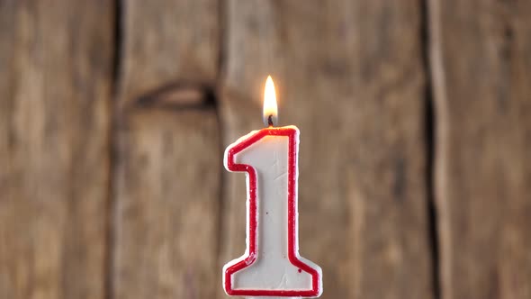 Candle fire on happy birthday celebration to 1 year old baby on wooden background