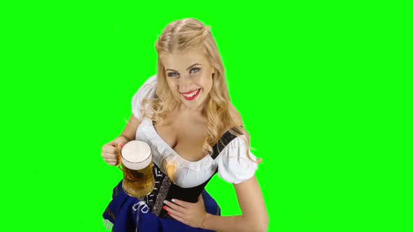 Bavarian Girl in Bavarian Costume Holding a Glass of Beer and Laughs. Green Screen