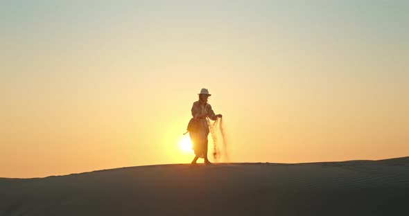 Happy Woman with Sand Blowing Away By the Wind with Golden Sunset on Background