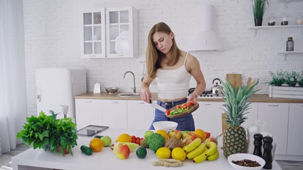 Young pretty woman preparing tasty salad on the modern kitchen