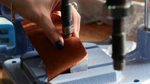 Female Craftsman Using Press for Installing Metal Rivet on Geniune Leather Product. Close Up