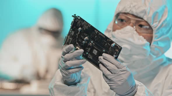 Engineer in Protective Suit Examining Computer Graphics Card