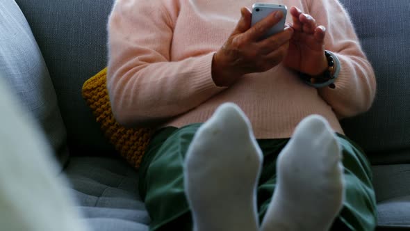 Senior woman using mobile phone in living room