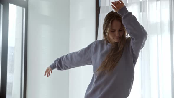 Young Woman with Long Hair Dancing By the Window in Daylight