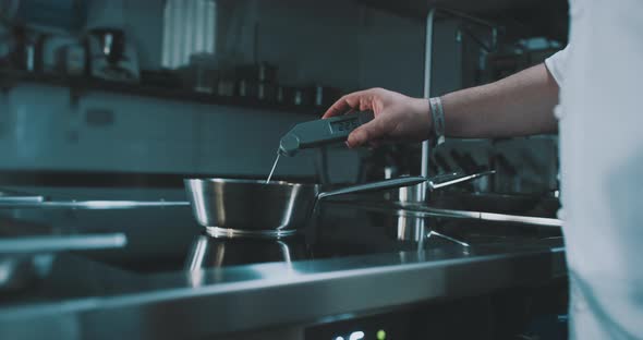 Chef tests temperature of water in pot