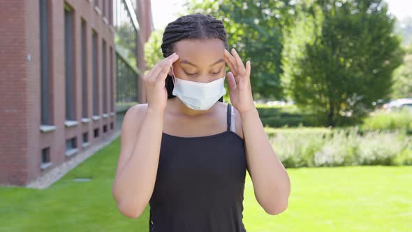 A Young Black Woman in a Face Mask Is Sick, Coughs and Has a Headache - an Office Building