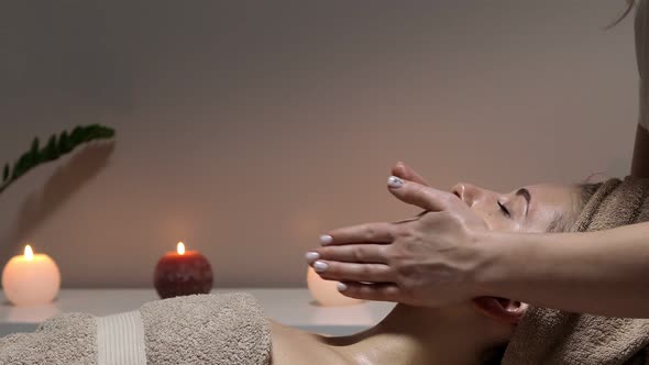 Closeup of young woman receiving professional head massage at spa.