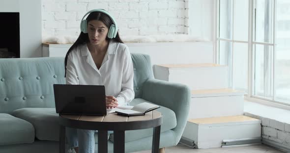 Serious Young Caucasian Woman Speaking By Video Call and Looking at Laptop