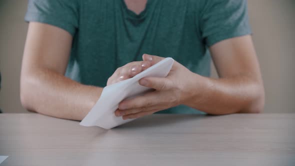 Man Is Folding a White Paper Airplane on the Table