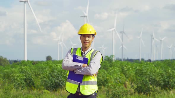 Portrait of Asian windmill engineer man, worker smiling, working on site at wind turbines field