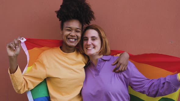 Happy gay couple celebrating pride holding rainbow flag outdoor - Lgbt and love concept