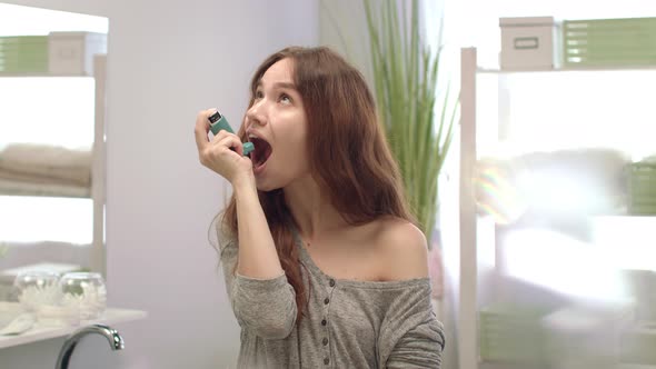 Happy Woman Using Inhaler for Fresh Breath in Bathroom. Dental and Teeth Care