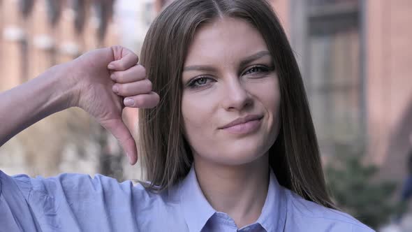 Thumbs Down By Young Woman at Work Looking at Camera