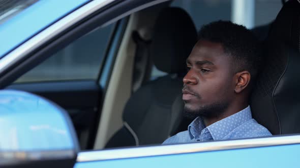 African American Driver Sits in Black Cabin of Blue Car