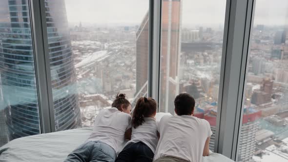 Young Family with Daughter Spending Time Together in Modern Apartment with Large Windows Overlooking