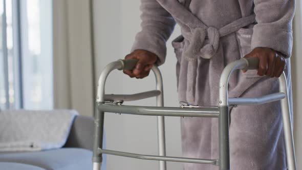 Mid section of senior man using zimmer frame to walk at home