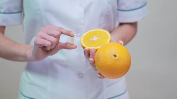 Nutritionist Doctor Healthy Lifestyle Concept - Holding Vitamin Pill and Orange Fruit