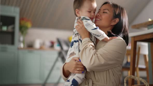 Lovely Asian mom kissing her son