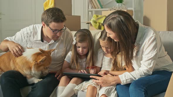 A Happy Family Uses a Tablet for Online Shopping Sitting on the Couch at Home