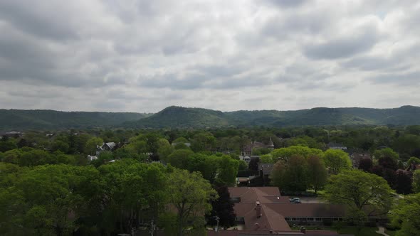 Flyover of older residential neighborhood with diverse structures and tree lined streets. Cloudy sky