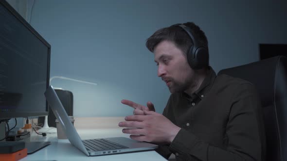 A Male Software Developer Makes a Videocall with Coworkers While Sitting at His Computer and Using p