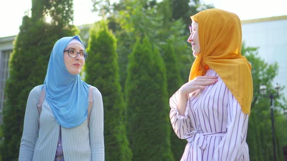 Two Young Deafmute Muslim Women in Traditional Scarves and Glasses Go and Communicate Using Sign