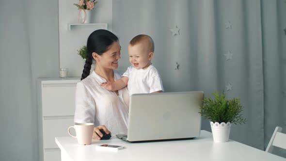 Mother Woman with a Toddler Working at the Computer