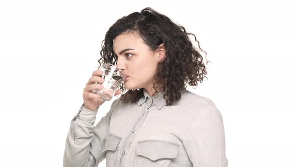 Portrait of Caucasian Lovely Woman with Dark Curly Hair Drinking Still Water From Glass Being