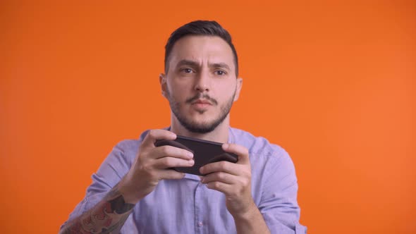 Young Man Playing on Smartphone with Both Hands, Moving Sideways. Front View, Studio Shot