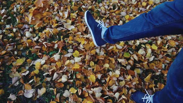 Man Legs in the Jeans Boots Walking on the Autumn Leaves in the Park Slow Motion