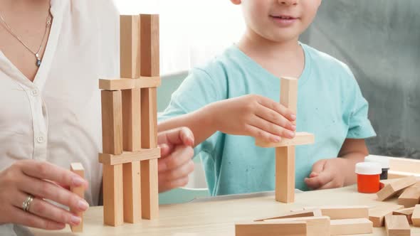 Smart Boy with Mother Playing with Wooden Toy Blocks and Building High Tower