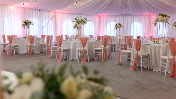 Banquet hall decorated for wedding party with fresh flowers. White and orange thematic for wedding p