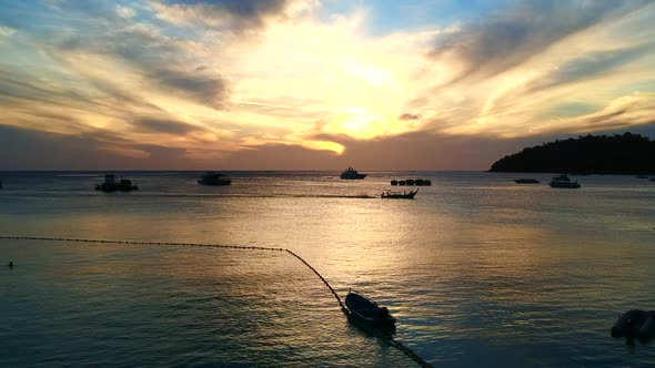 A picturesque,  colourful sunsets with reflection falling to the ocean and boats.